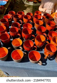 Merchandise on annual biggest crafts market in Latvian Ethnographic Open Air museum. Bright orange and red traditional glazed ceramic cups and bowls. Riga, Latvia - June 4, 2022