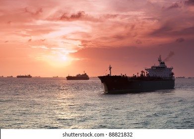 Merchant Ships In Silhouette Backlit By The Sun Set