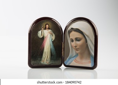 Merciful Jesus and Our Lady of Medjugorje, the Blessed Virgin mary, icons in a wooden rounded case isolated on white backgrounds with shady reflection on white table.
