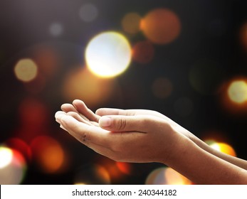 Mercy and forgiveness concept: Kid open empty hands with palms up over bokeh of candle light background