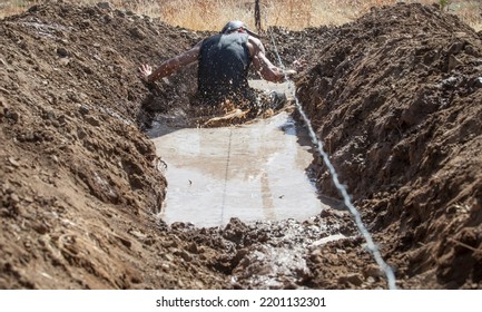 Merida, Spain - Sept 11th, 2022: FarinatoRace Merida 2022. Toughest Obstacle Course In The World. Trench Flooded With Barbed Wire