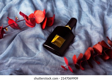 MERIDA-YUCATAN-MEXICO-MARCH-2022: Black Orchid Perfume by Designer Tom Ford, which is lying on its side on a blue fabric background and decorative leaves..
