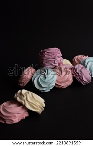 Meringue homemade Marshmallow Zephyr on black contrast trendy background.  Pink and sweet. Colorful dessert. Cookie rosette shape.
