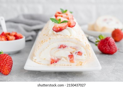 Meringue roll Pavlova cake with cream and fresh strawberries on top on a gray background. Copy space.