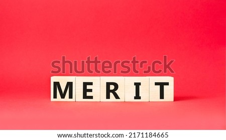 Merit symbol. Concept word Merit on wooden cubes. Beautiful red background. Business and Merit concept. Copy space.