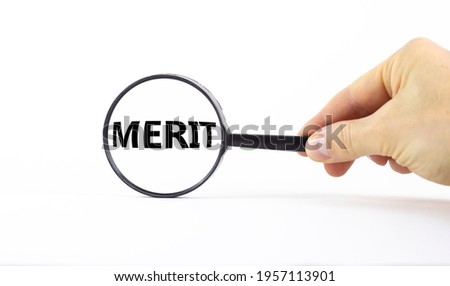 Merit symbol. Magnifying glass with word merit on a beautiful white background. Businessman hand. Business and merit concept, copy space.