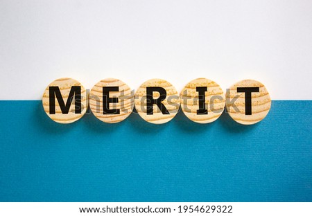 Merit symbol. Wooden circles with the word 'merit'. Beautiful white and blue background, copy space. Business and merit concept.