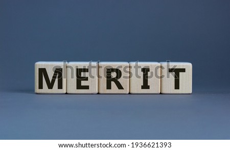 Merit symbol. Wooden cubes with the word 'merit'. Beautiful grey background, copy space. Business and merit concept.