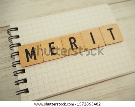 Merit word in wooden blocks on notebook