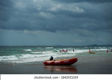 Mermaid Beach QLD Australia 10/25/2020: Surf Life Saving Water Craft Parked On The Shore Ready For A Rescue With A Group Of Little Nippers Board Training In The Background On A Stormy Day.