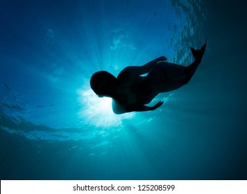 Mermaid Silhouette, Beautiful Young Women Free Diving In The Deep Blue Wearing A Mermaid Tail Monofin