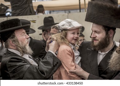 MERON,ISRAEL- MAY 26, 2016: An Unidentified Hasidic Rabbi Gives First Haircut To An Unidentified Jewish Hasidic Boy With Blond Curls As Is Tradition Upon The Grave Of Rabbi Shimon On Lag Ba'omer.