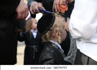 MERON,ISRAEL- MAY 26, 2016: An Unidentified Hasidic Rabbi Gives First Haircut To An Unidentified Jewish Hasidic Boy With Blond Curls As Is Tradition Upon The Grave Of Rabbi Shimon On Lag Ba'omer.

