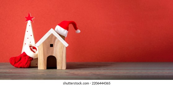 Merry chistmas and happy new year with wooden home wear santa hat on wood table with vivid red background