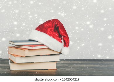 Merry Christmas. Books and Santa Claus hat on a wooden table. Christmas concept background