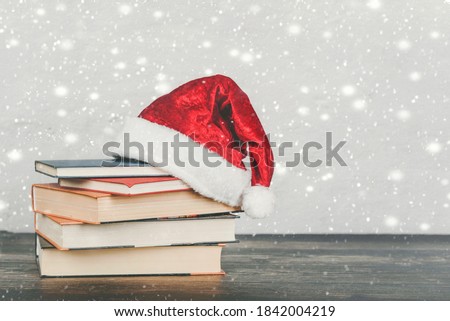 Merry Christmas. Books and Santa Claus hat on a wooden table. Christmas concept background