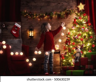 Merry Christmas! Cute little child girl is decorating the Christmas tree.