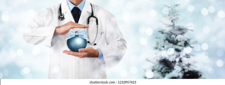 Merry Christmas from doctor,, best wishes concept, hands with xmas ball on blurred light and tree, gift card banner web template with copy space