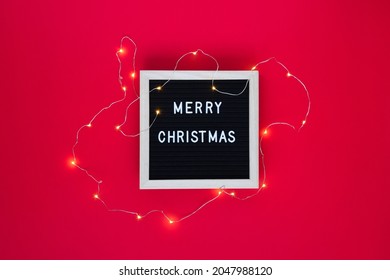 Merry Christmas Greeting On Letter Board With Fairy Lights On Red Background