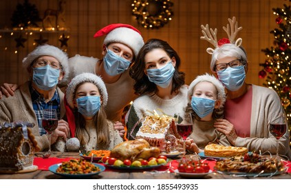 Merry Christmas! Happy Family Are Having Dinner At Home. Celebration Holiday And Togetherness Near Tree. People Are Wearing Facemasks.