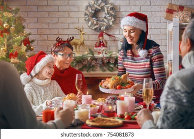 Merry Christmas! Happy Family Are Having Dinner At Home. Celebration Holiday And Togetherness Near Tree.