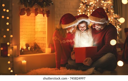 Merry Christmas! happy family mother father and child with magic gift near tree - Shutterstock ID 745824997