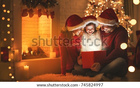 Merry Christmas! happy family mother father and child with magic gift near tree
