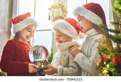 Merry Christmas and Happy Holiday! Cute little children with snow globe near tree at home.  - Powered by Shutterstock