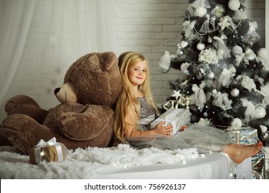 Merry Christmas and Happy Holiday. Pretty blonde girl with long hair is holding big teddy bear