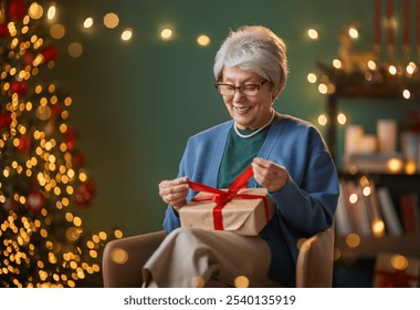 Merry Christmas, Happy Holidays. Cheerful senior woman having got a Christmas present.  - Powered by Shutterstock