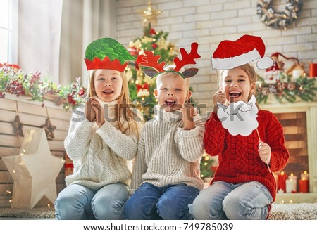 Merry Christmas and Happy Holidays! Children with paper accessories for photo: Santa hat, antlers of a reindeer and the elf headdress. Family party.