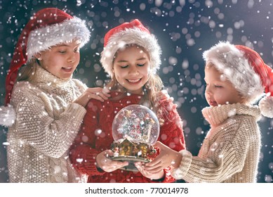 Merry Christmas and happy holidays! Cute little children with snow globe. Kids enjoying the holiday on dark background. - Powered by Shutterstock