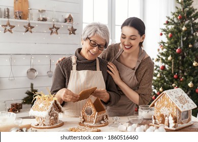 Merry Christmas And Happy Holidays. Family Preparation Holiday Food. Mother And Daughter Cooking Gingerbread House.