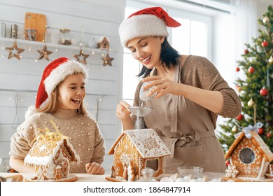 Merry Christmas And Happy Holidays. Family Preparation Holiday Food.Mother And Daughter Cooking Gingerbread House.