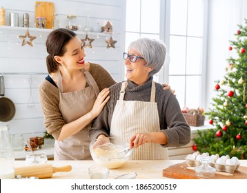 Merry Christmas And Happy Holidays. Family Preparation Holiday Food. Mother And Daughter Cooking Gingerbread House.