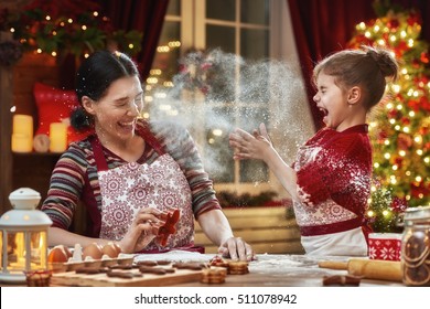 Merry Christmas and Happy Holidays. Family preparation holiday food. Mother and daughter cooking Christmas cookies.