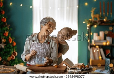Merry Christmas and Happy Holidays. Family preparation holiday food. Grandmother and granddaughter cooking cookies.