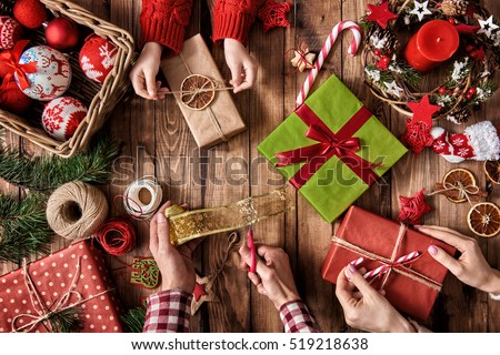 Merry Christmas and Happy Holidays! A mother, father and their daughter prepare Xmas gifts. Baubles, presents, candy with christmas ornaments. Top view. Christmas family traditions.