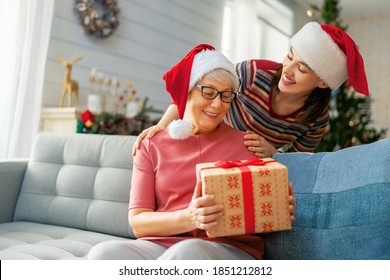 Merry Christmas and Happy Holidays! Senior mom and her adult daughter exchanging gifts. Having fun near tree indoors. Loving family with presents in room.  - Powered by Shutterstock