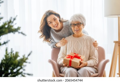 Merry Christmas, Happy Holidays. Senior mom and her adult daughter exchanging gifts. Having fun near tree indoors. Loving family with presents in room.  - Powered by Shutterstock