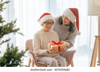 Merry Christmas, Happy Holidays. Senior mom and her adult daughter exchanging gifts. Having fun near tree indoors. Loving family with presents in room.  - Powered by Shutterstock