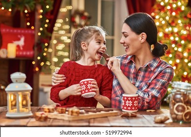 Merry Christmas and Happy Holidays. Time of family tea party. Mother and her child daughter are drinking warm tea with Christmas cookies.  - Powered by Shutterstock