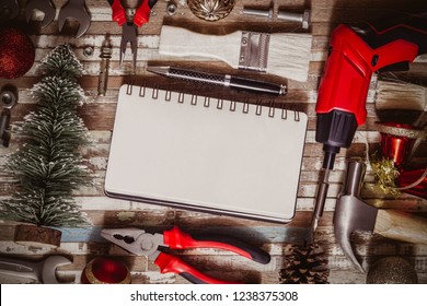 Merry christmas and Happy New year Craftsman Workspace background concept, Variety of handy DIY tools with Christmas ornament decoration. Top view with blank space notebook for your text.