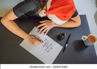Merry christmas and a happy new year. Calligrapher Young Woman writes phrase on white paper. Inscribing ornamental decorated letters. Calligraphy, graphic design, lettering, handwriting, creation
