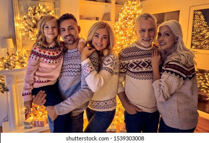 Merry Christmas And Happy New Year! Happy Family Celebrating Winter Holiday At Home. Grandparents, Parents And Children Waiting For Christmas While Standing Near Decorated New Year Tree Together