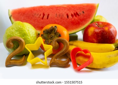 Merry Christmas And Happy New Year 2020 Texts With Star And Heart Molds .Event To Celebrate With Fruits Is Healthy Food Such As Watermelon,apple,banana, Persimmon And Guava Fruit.