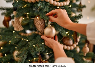 Merry Christmas and Happy New Year! Women's hands decorate the Christmas tree with balls and toys.