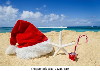 Merry Christmas And Happy New Year Background With Santa Claus Hat And Starfish On The Tropical Beach Near Ocean In Hawaii