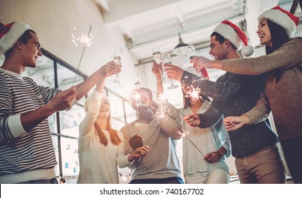 Merry Christmas and Happy New Year 2018! Multiracial young creative people are celebrating holiday in modern office. Group of young business people are drinking champagne in coworking. 