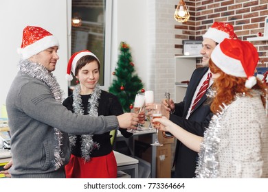 Merry Christmas and Happy New Year 2018. Team is celebrating holiday in modern office. Group of young business people are drinking champagne in coworking.